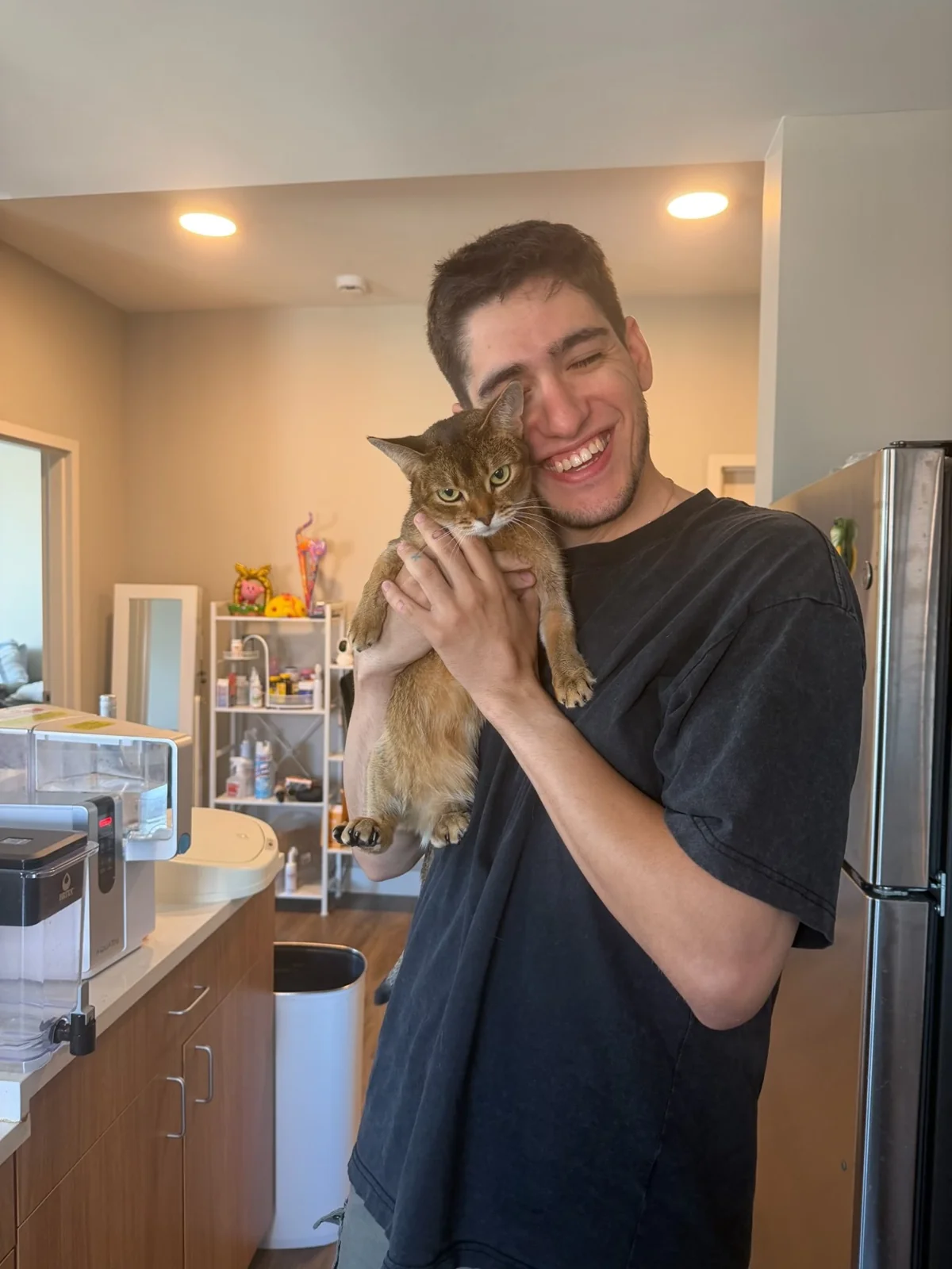 Renilson smiling while holding his cat Kola